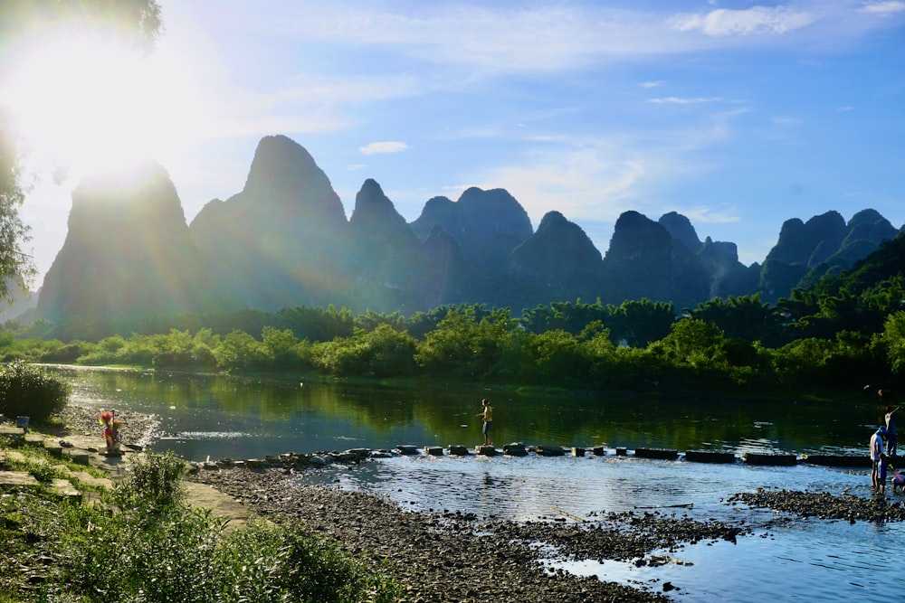a body of water with a group of people standing on it and Li River in the background