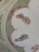 A beautifully painted ceiling features classical figures in flowing garments surrounded by ornate floral arrangements. The figures are depicted in dynamic poses, seemingly floating and carrying objects. The background showcases intricate ornamental designs enhancing the elegance of the scene.