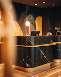 A black marble reception desk with gold trim in a hotel lobby