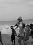 Group of children and volunteers on a beach, sharing a joyful moment