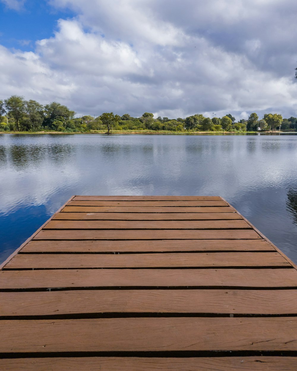 a wood dock over a body of water with trees in the background