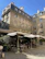Outdoor café seating shaded by a stylish, neutral-toned umbrella on a sunny day.