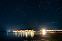 Shadowy overwater villa perched on stilts, illuminated subtly against a dark ocean backdrop.
