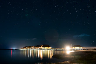 Overwater bungalow glowing warmly under a starry night sky.