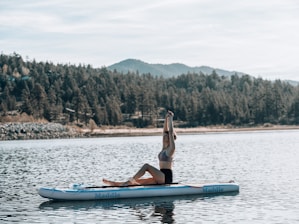 a person doing a handstand on a paddle board in a lake