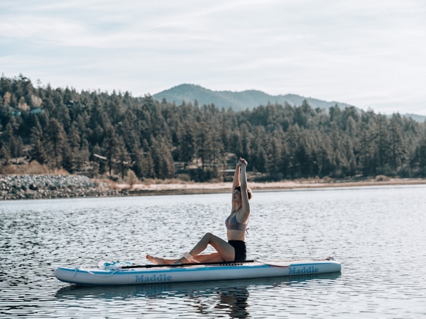 a person doing a handstand on a paddle board in a lake
