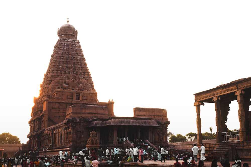 um grande templo com pessoas em pé ao redor com o Templo Brihadeeswarar ao fundo