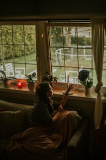 A cozy indoor scene with a woman lounging in an oversized etete wear cardigan by a window.