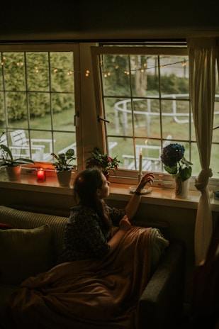 A cozy indoor scene with a woman lounging in an oversized etete wear cardigan by a window.