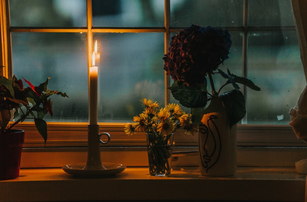 a candle next to a vase of flowers