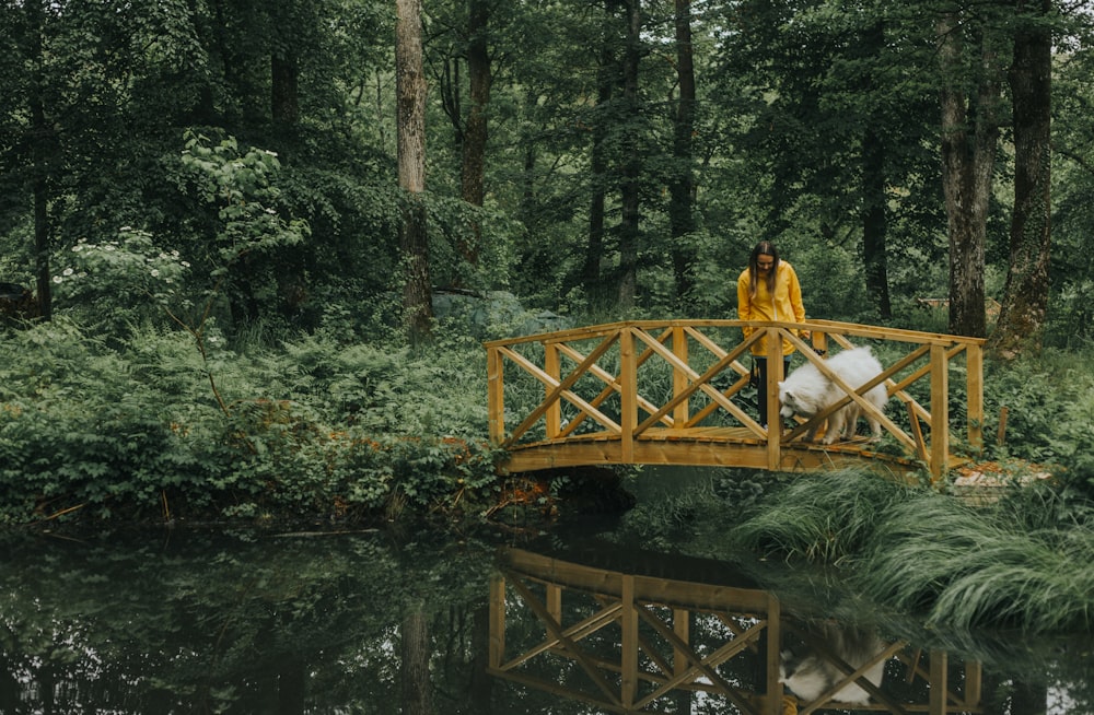 a person in a yellow raincoat on a wooden bridge over a river