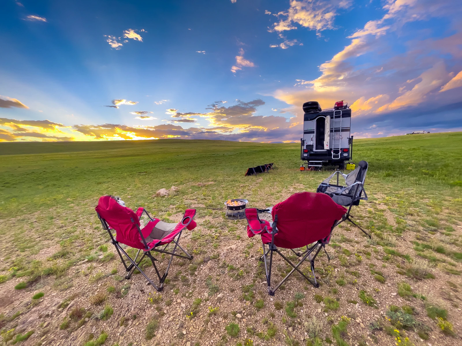 Two camp chairs set up in an open field on a summer day
