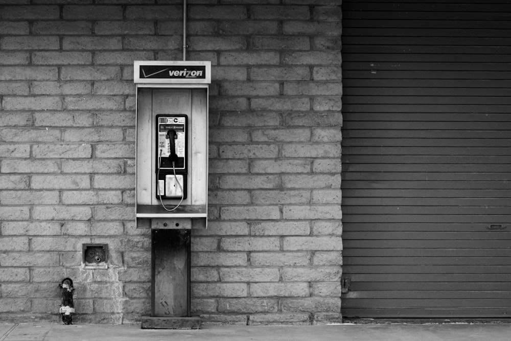 a telephone booth on a brick wall