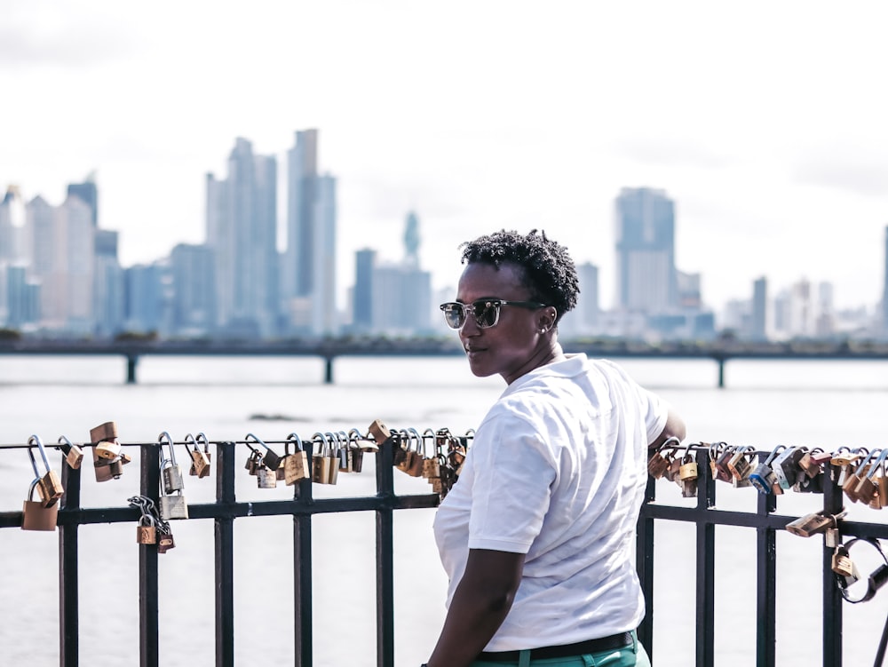 a person standing by a railing with a city in the background