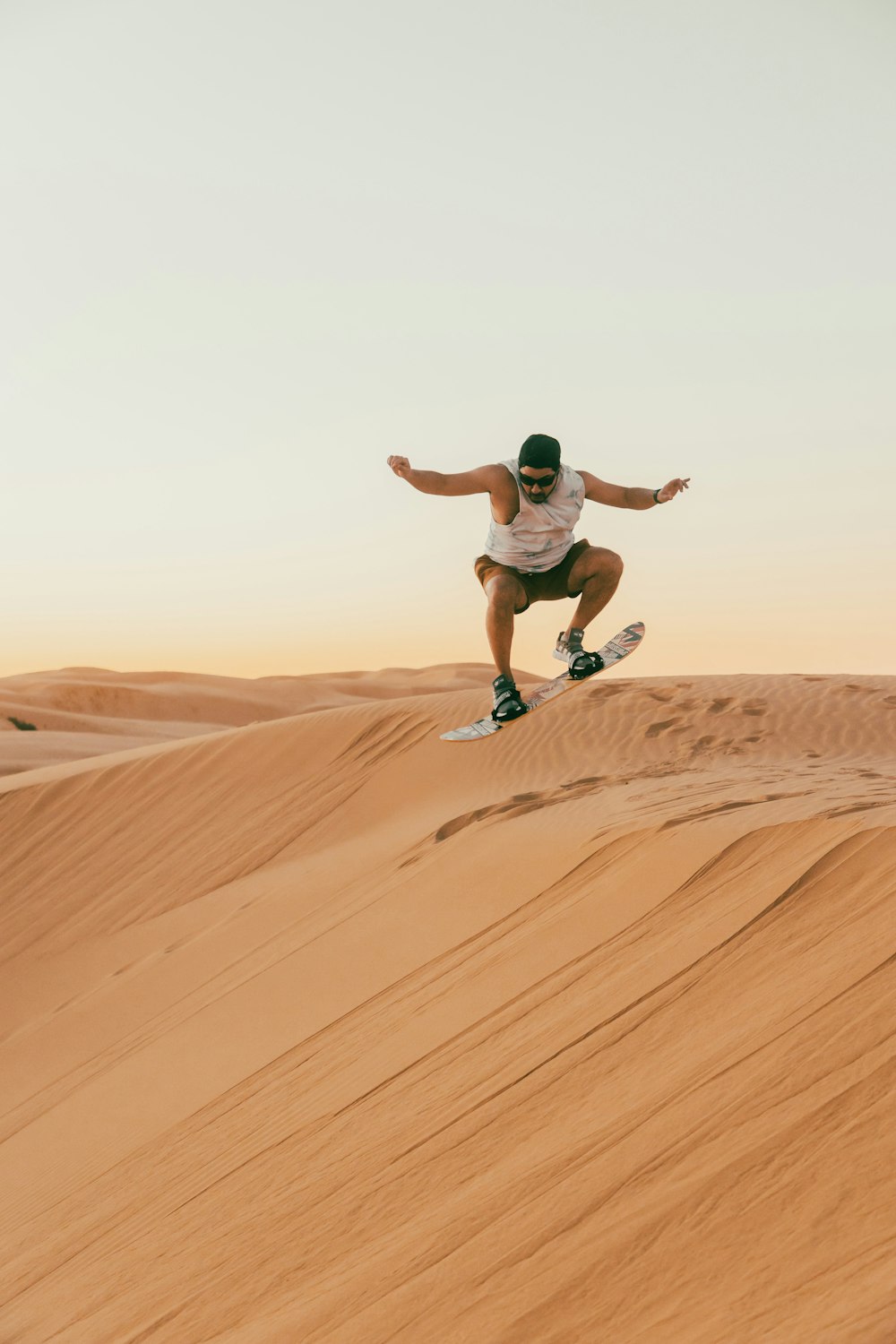 Un uomo che cavalca uno skateboard giù per una collina di sabbia