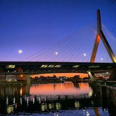 A stunning cable-stayed bridge under construction spanning a wide river at sunset