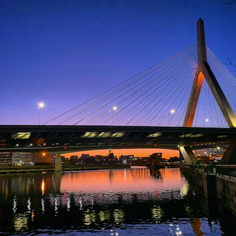 A stunning cable-stayed bridge under construction spanning a wide river at sunset