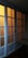 A set of sliding glass doors with a wooden frame, partially illuminated by a warm light from behind. The panels are arranged in a grid pattern, casting a soft glow through the translucent glass.