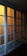 A set of sliding glass doors with a wooden frame, partially illuminated by a warm light from behind. The panels are arranged in a grid pattern, casting a soft glow through the translucent glass.