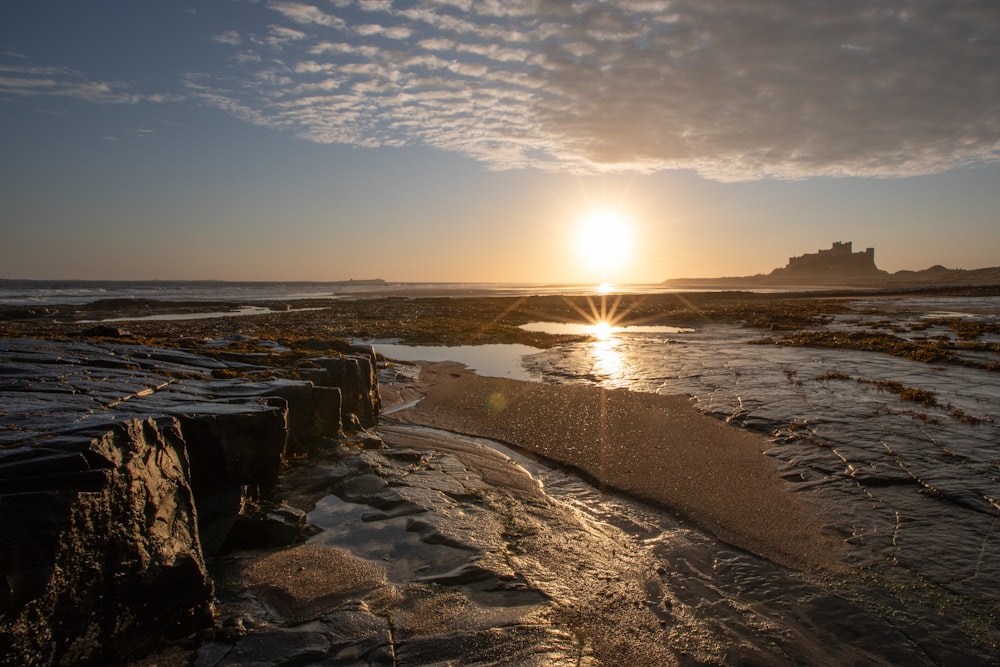 a rocky beach with the sun setting