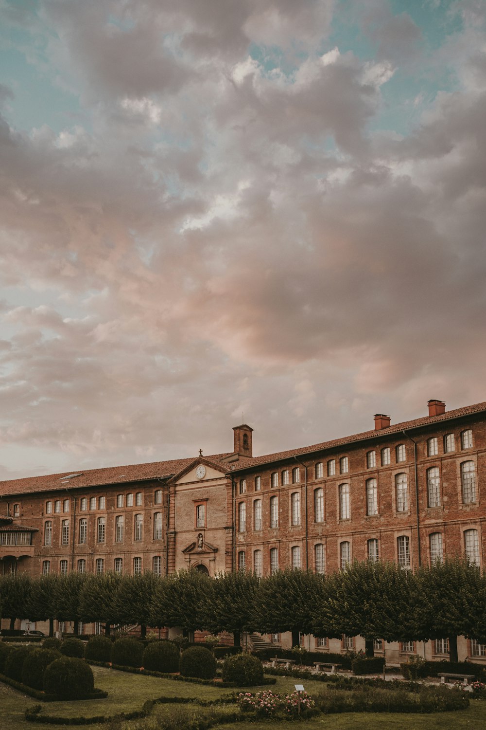 a large brick building with a garden in front of it