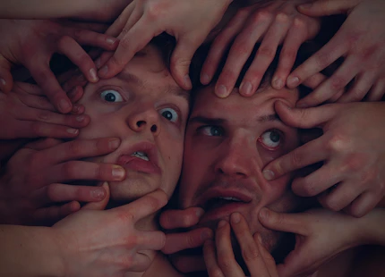 Close-up of hands demonstrating precise face yoga movements on a participant.