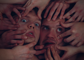 A close-up of hands performing face yoga exercises.