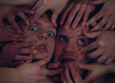 A close-up of hands performing face yoga exercises.