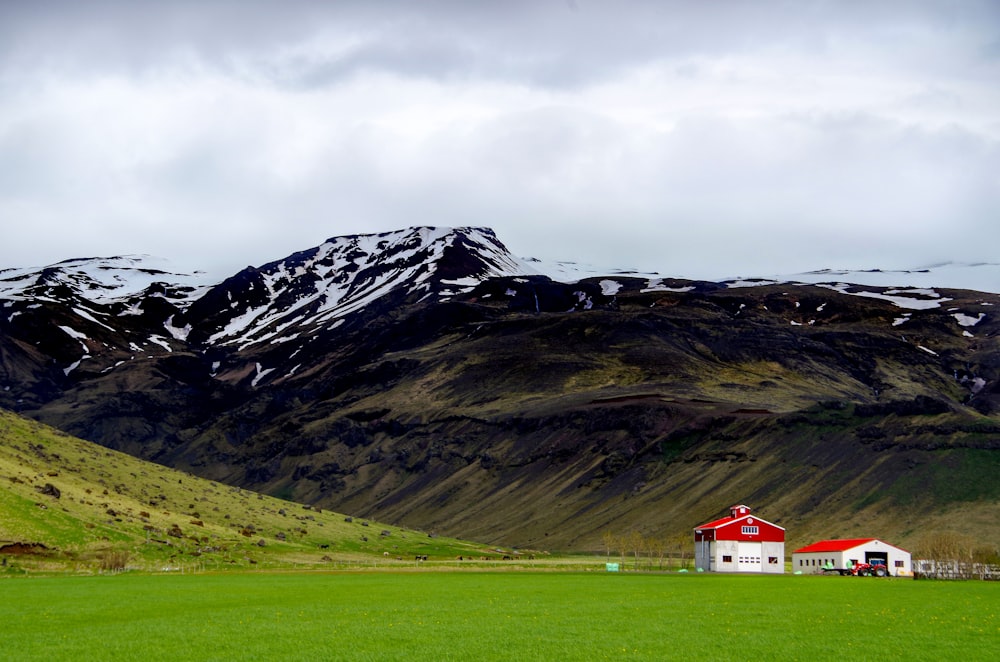 a couple of buildings in a field with mountains in the background