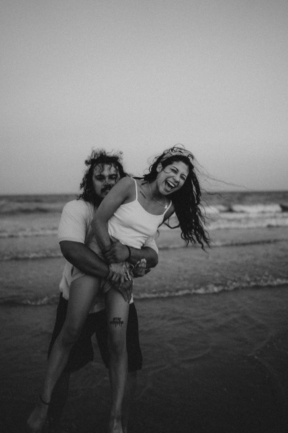 a man and woman posing on a beach