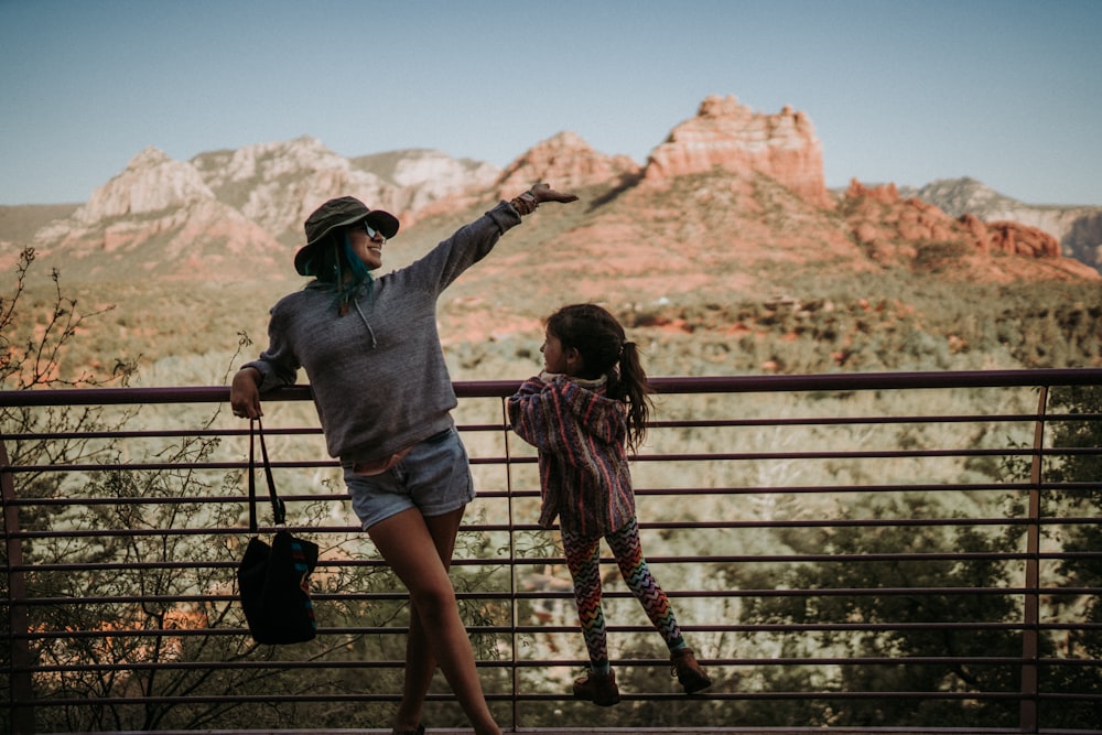 a person and a girl standing on a fence overlooking a canyon