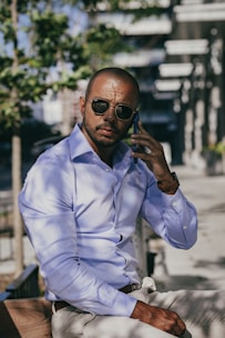 a man wearing sunglasses and a blue shirt sitting on a bench