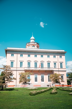 a large white building with a green lawn in front of it