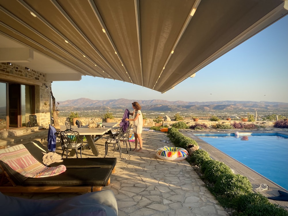 a couple of women standing on a patio with tables and chairs and a body of water in the