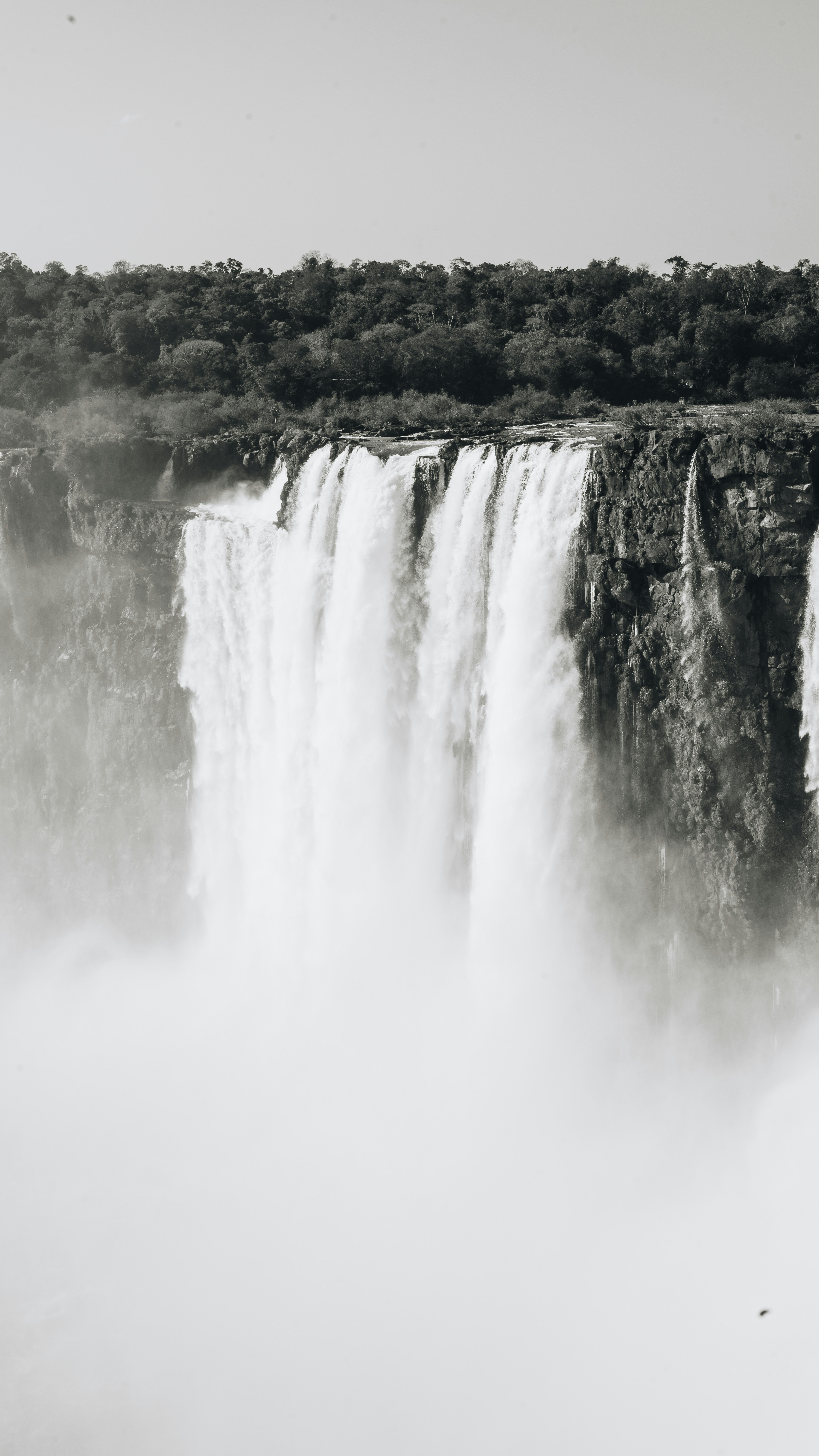 a large waterfall with trees in the background
