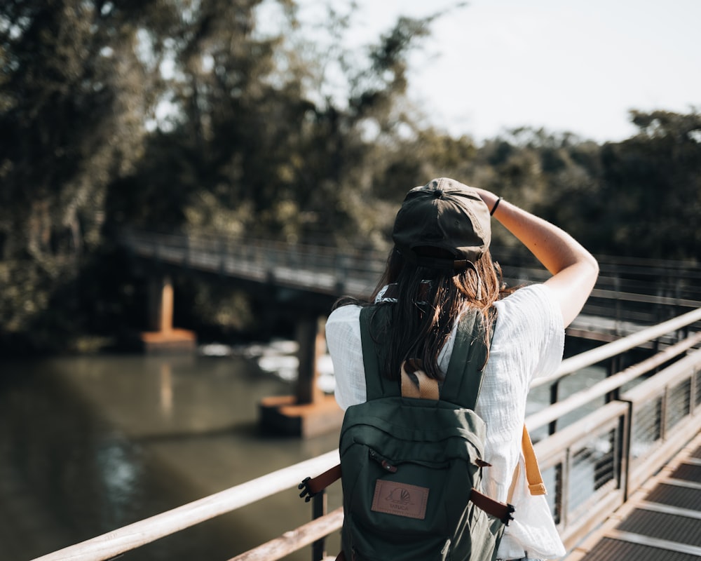 a woman with a backpack walking on a bridge