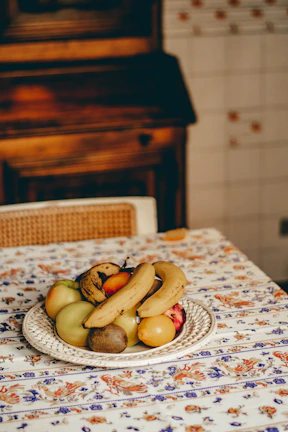 A bright yellow stoneware plate filled with fresh fruit, set against a warm linen tablecloth.