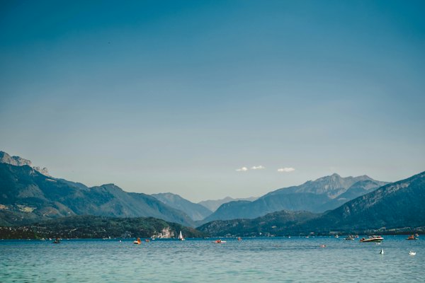 A body of water with boats and mountains in the background — Annecy, France