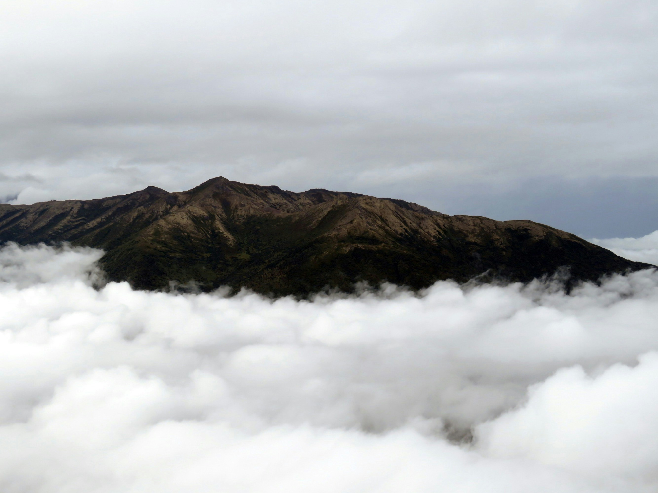 a mountain with clouds below, 