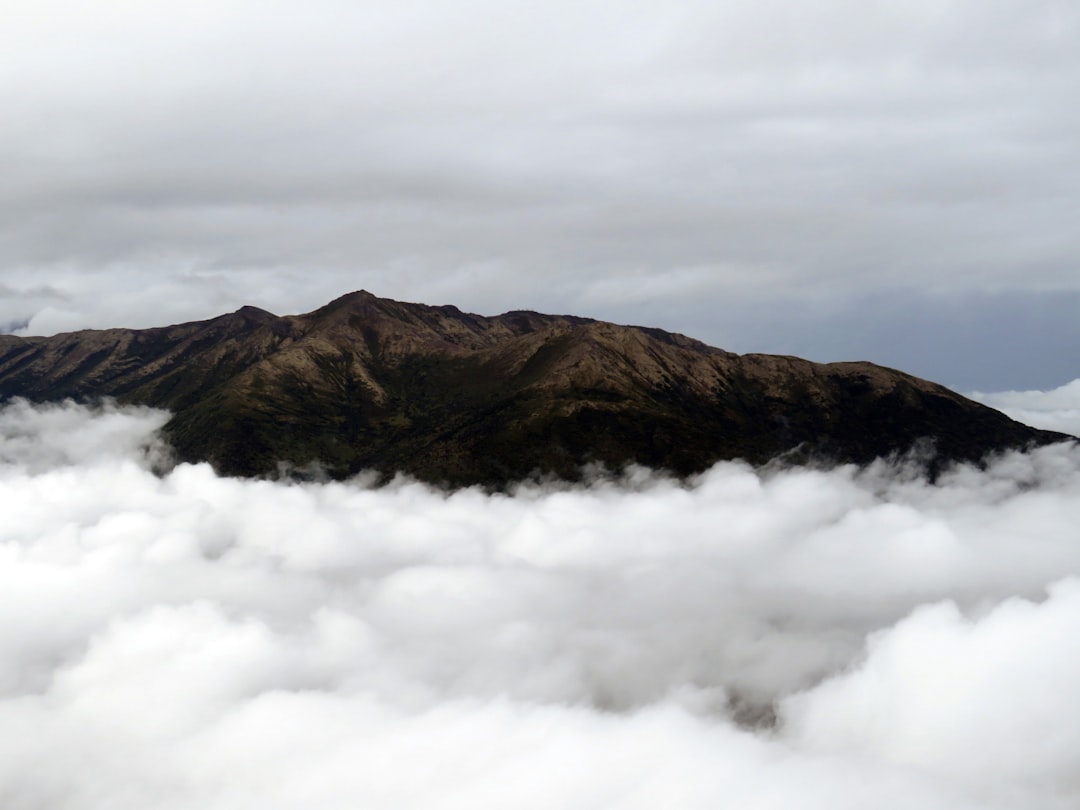 a mountain with clouds below,