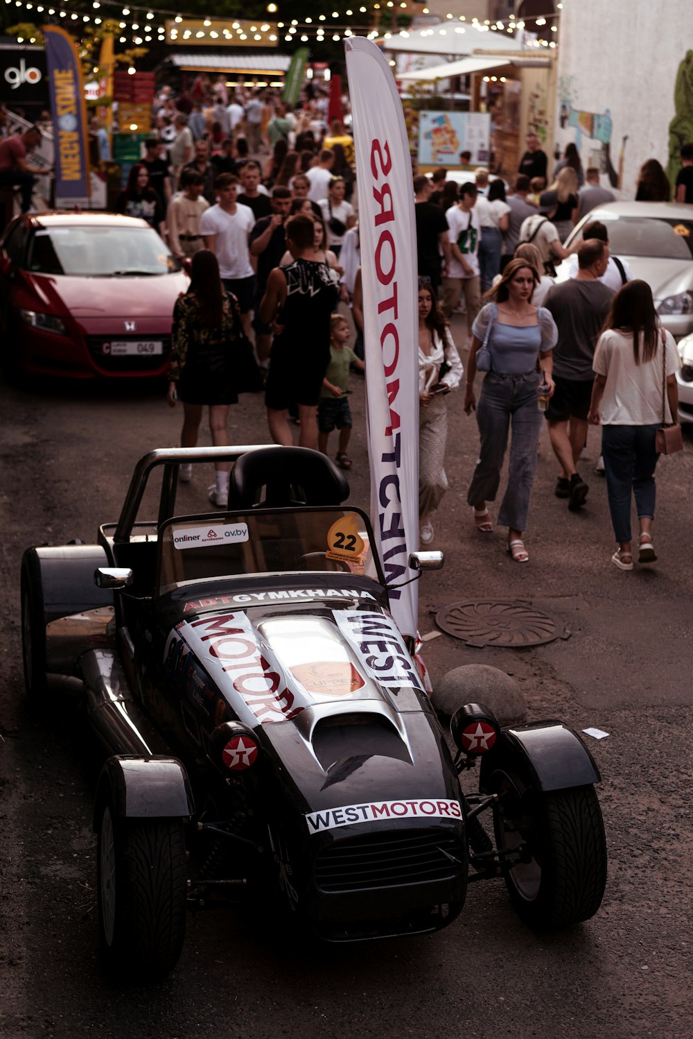 a race car on a street with people walking around
