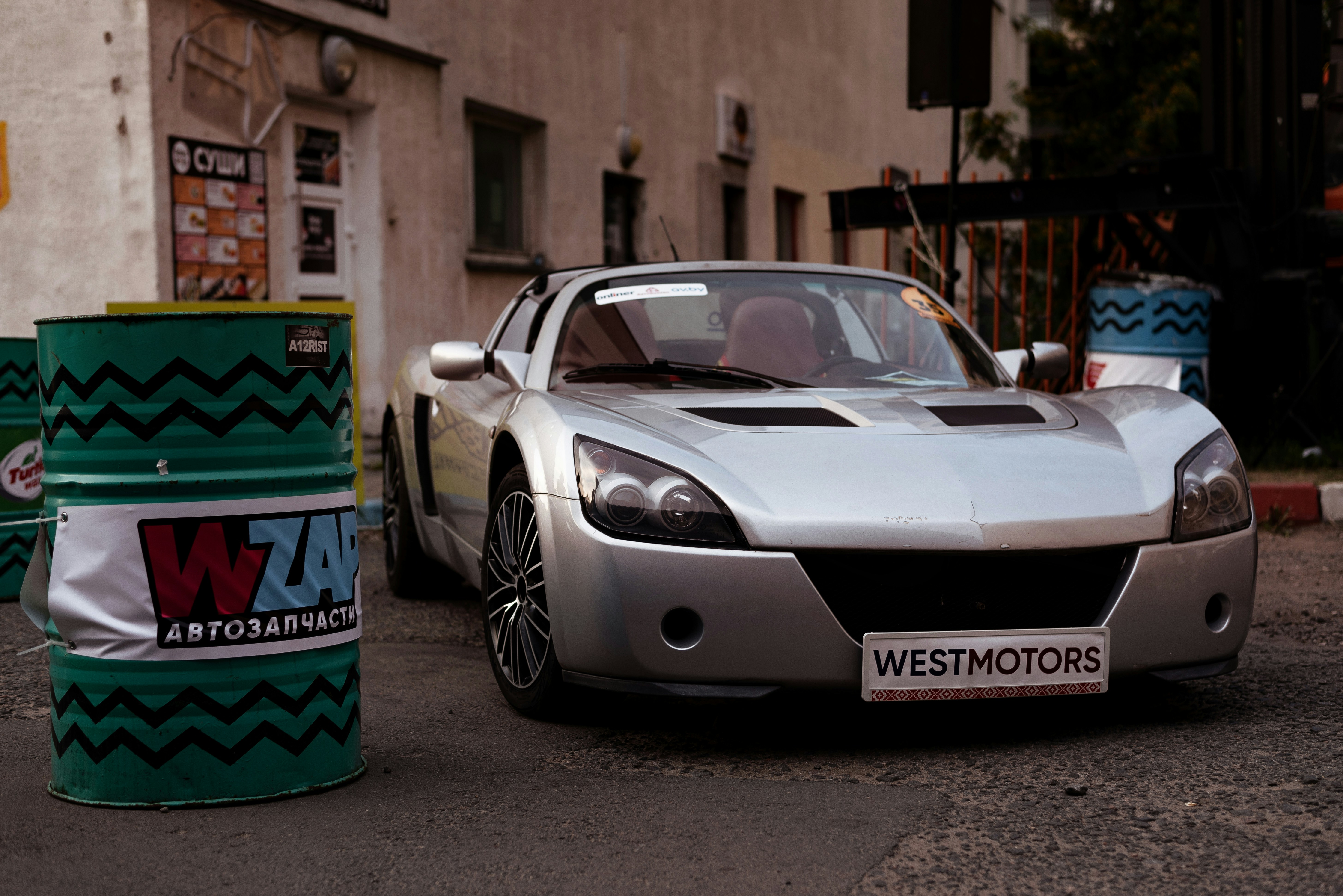 a silver car parked next to a green can