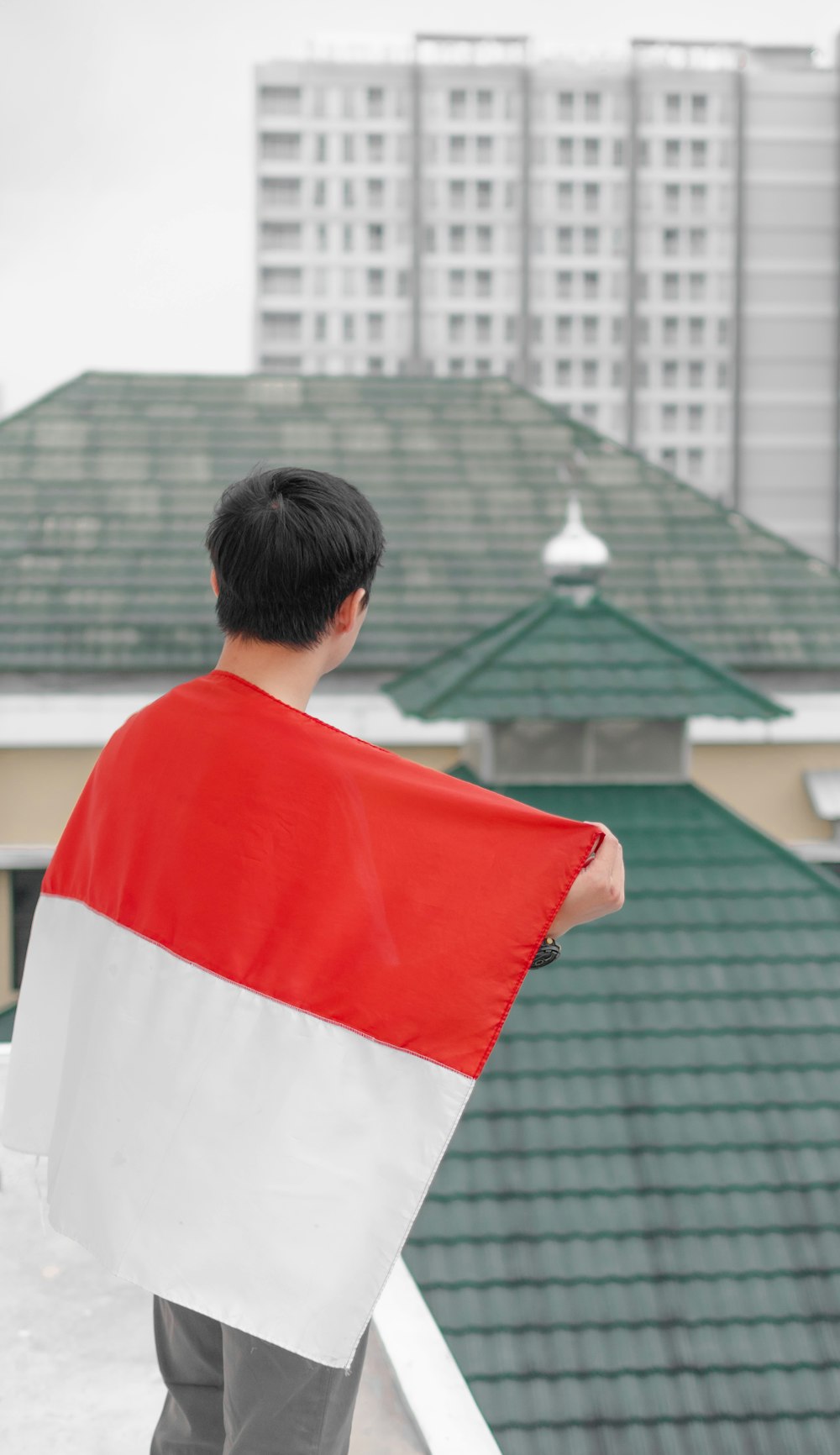 a man wearing a red and white shirt and standing on a roof