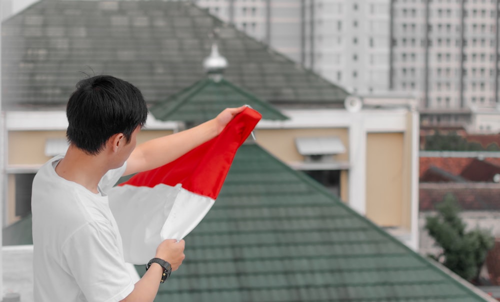 a person holding a red and white flag in front of a building