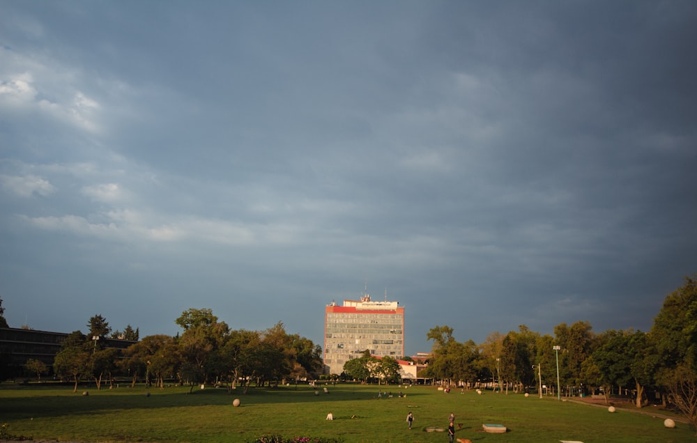 a large grassy field with trees and a building in the background
