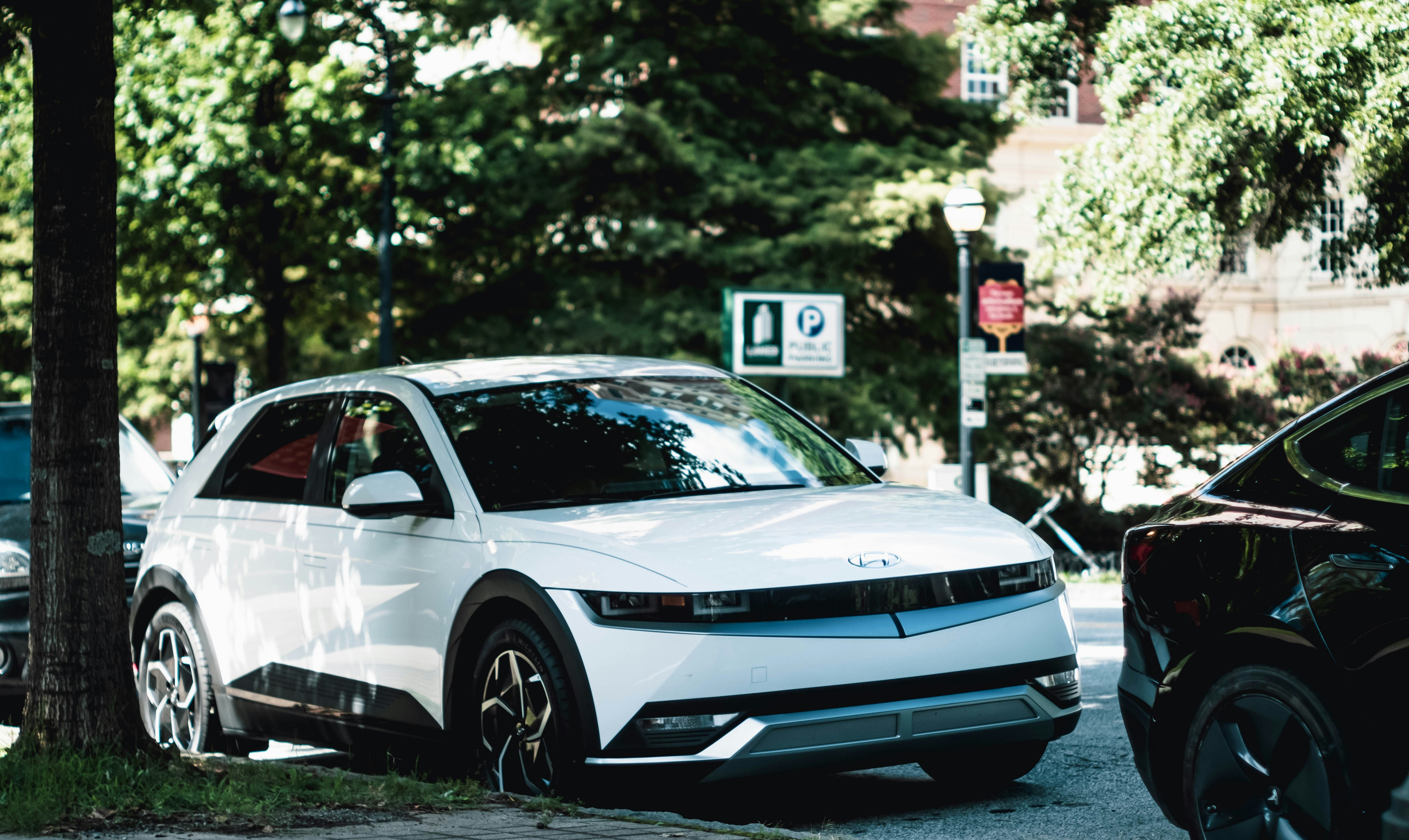 A compact used electric car plugged into a public charger on a city street