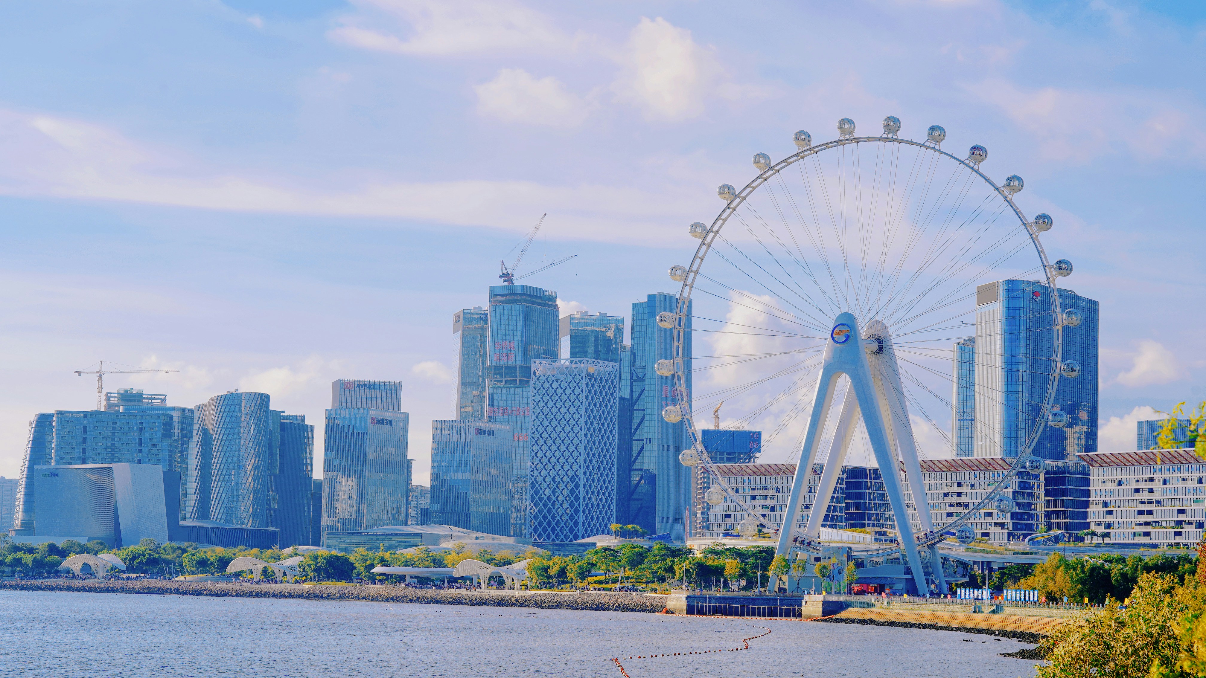 a ferris wheel by a body of water with buildings in the background