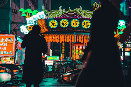 A lively street scene in Marrakech glowing with neon lanterns and bustling market stalls under a twilight sky.