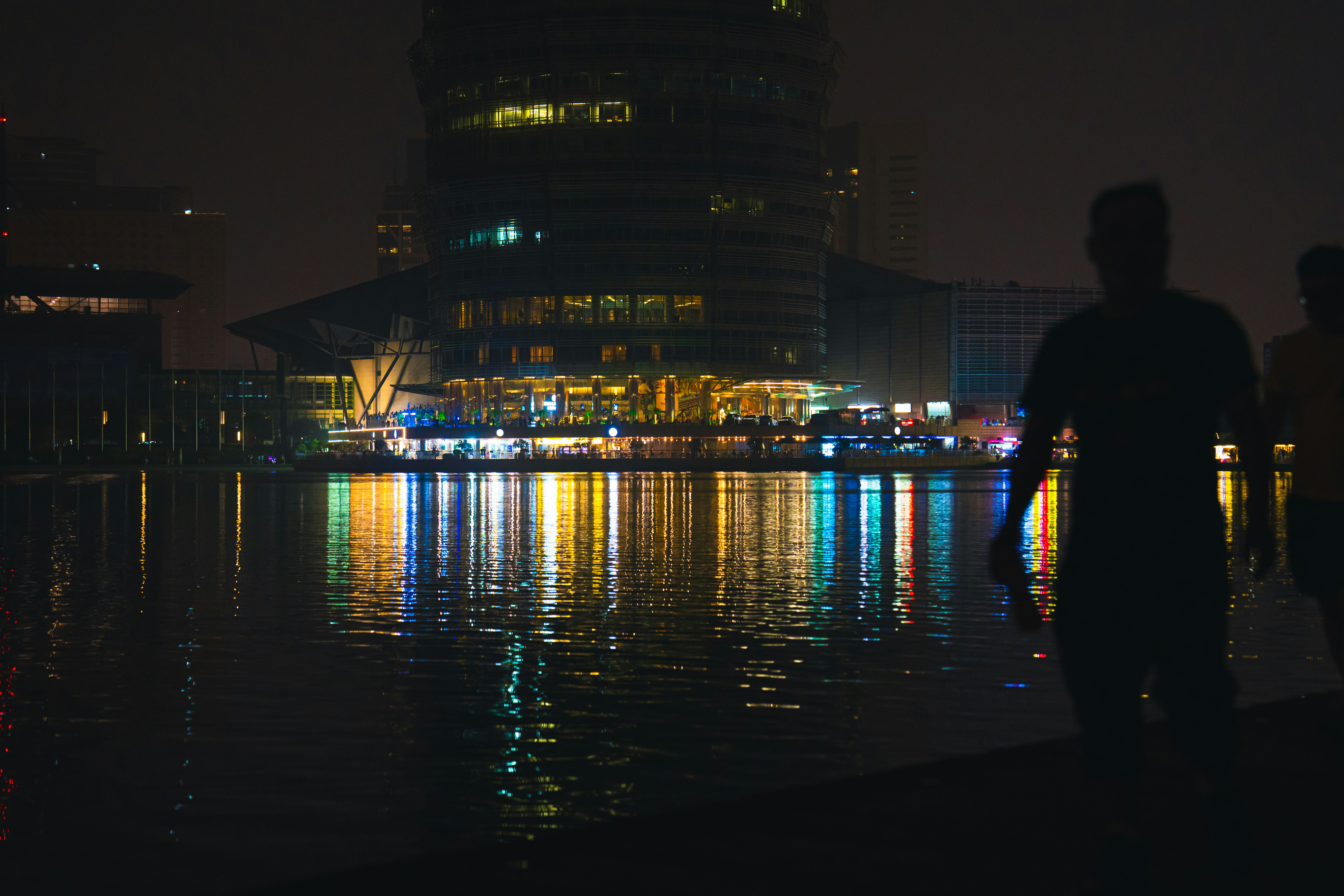 a person standing next to a body of water with a building in the background