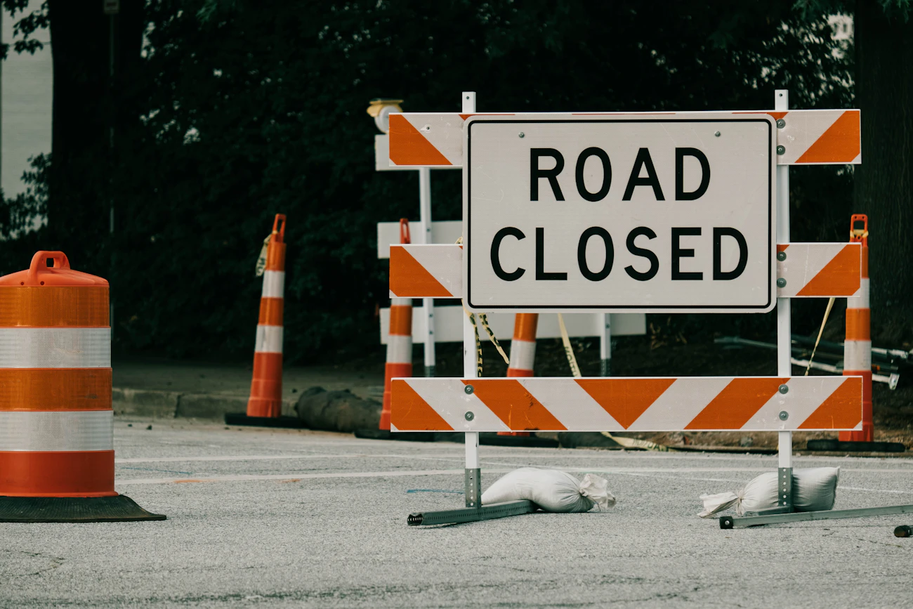 Road closed sign with orange cones and barriers